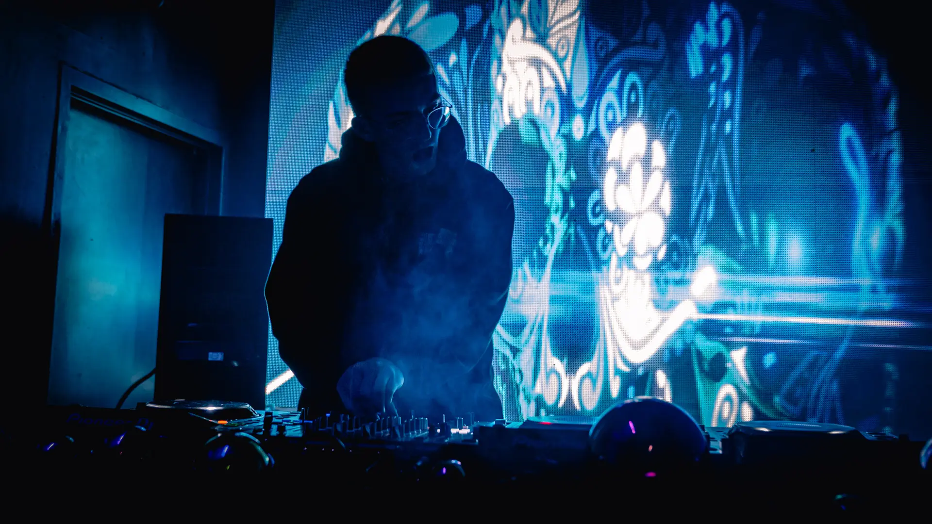 lucidlou DJing in silhouette in front of an LED wall
